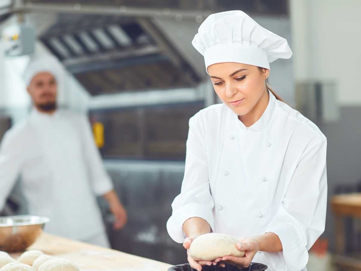 Apprentice baker shaping a loaf of bread at a bakery