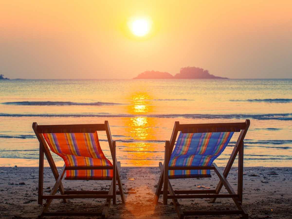 A pair of beach loungers on the deserted beach at sunset.