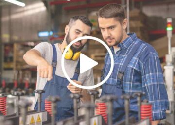 a group of men in overalls looking at a machine