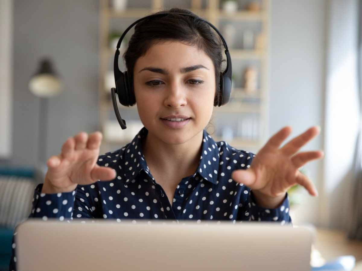 Young business woman wearing wireless headset participating in online training