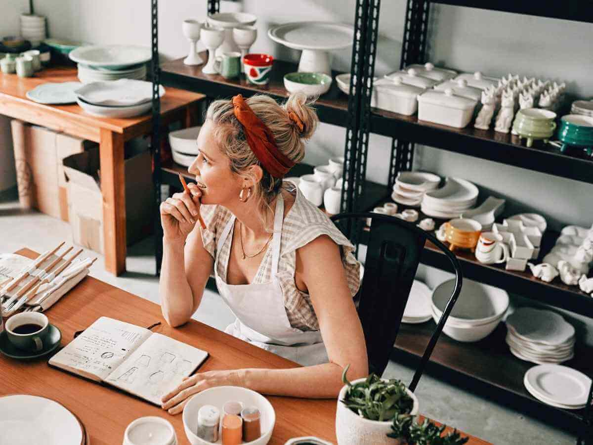 Pay less business tax article - image of a mature woman sitting alone and looking contemplative in her pottery business.