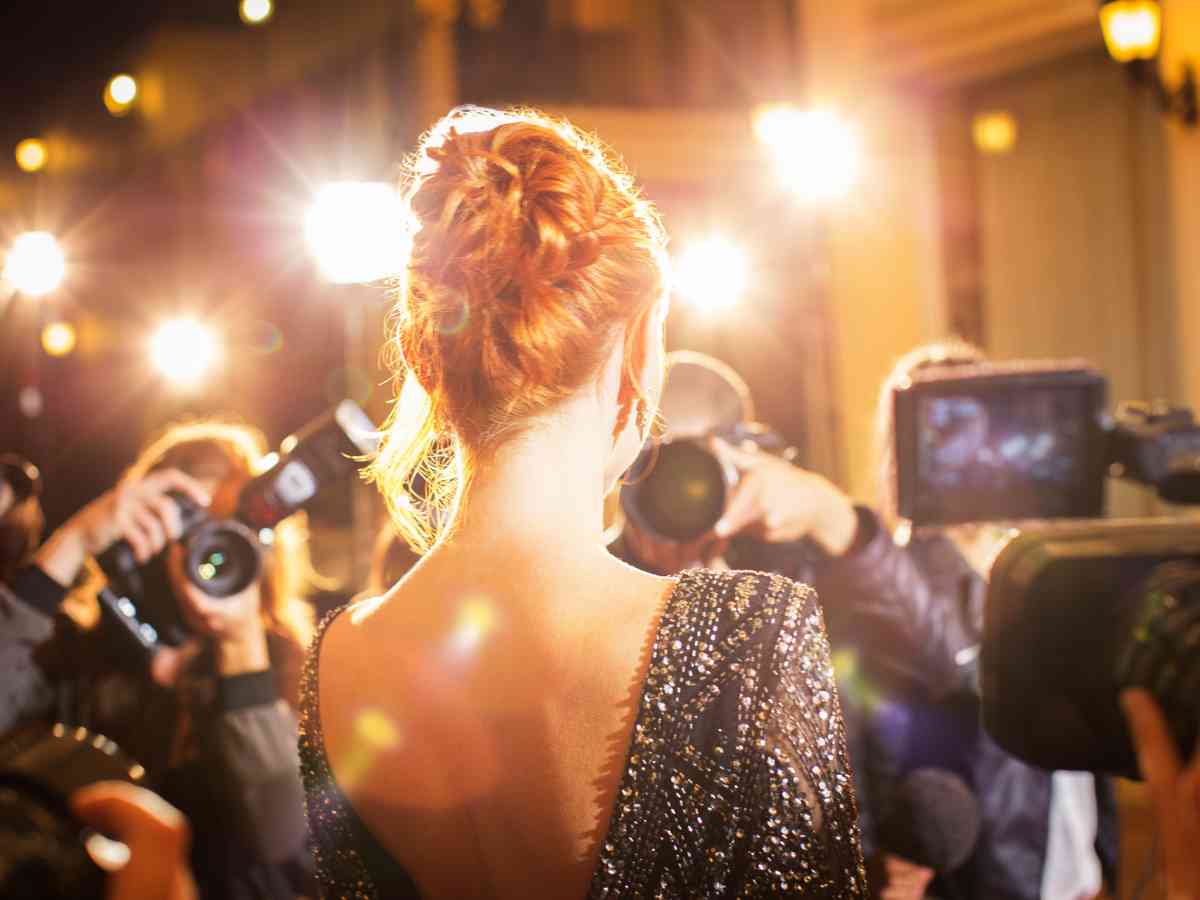 A celebrity being photographed by paparazzi at an event