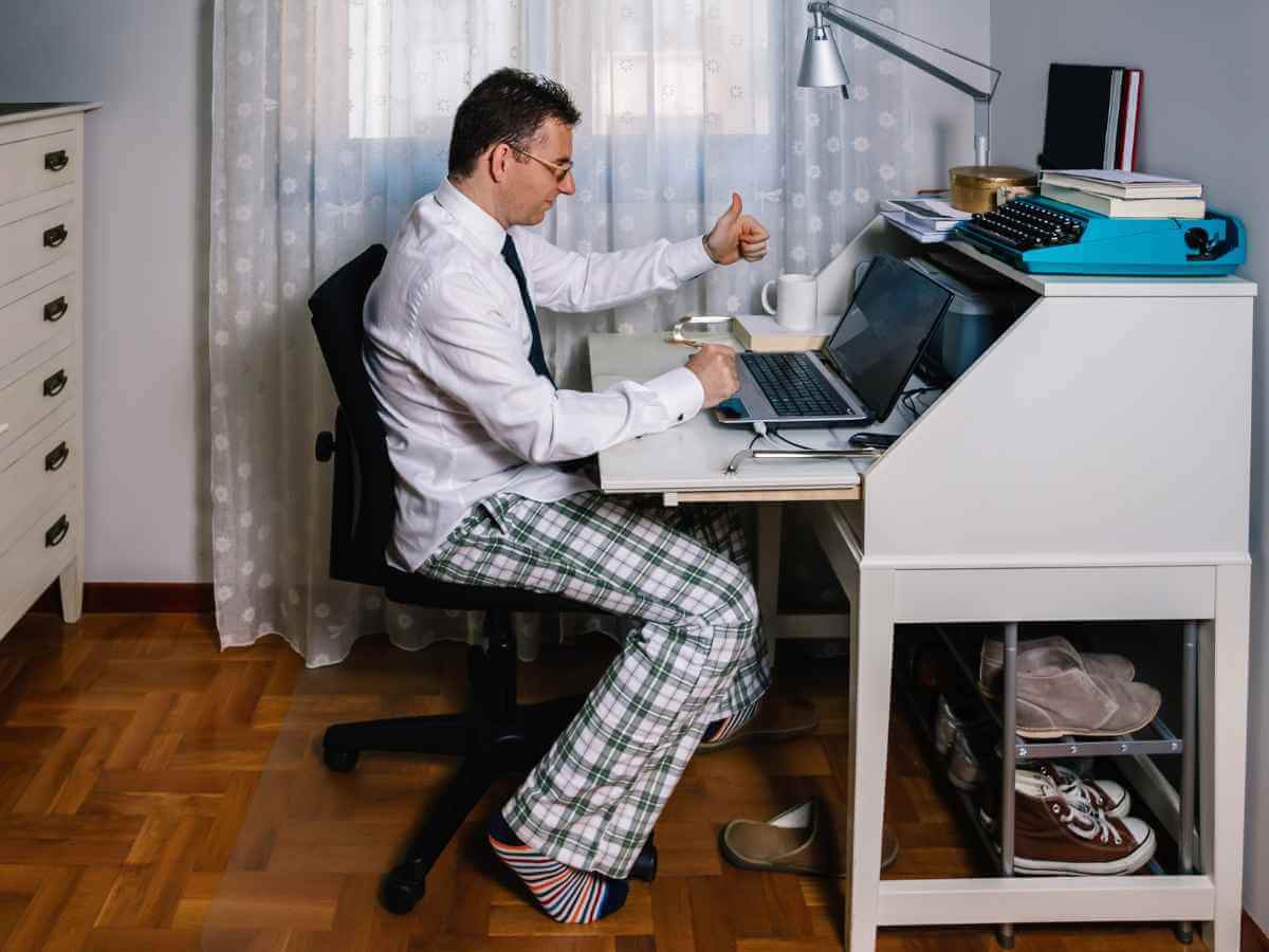 Man working from home with laptop wearing shirt, tie and pyjama pants