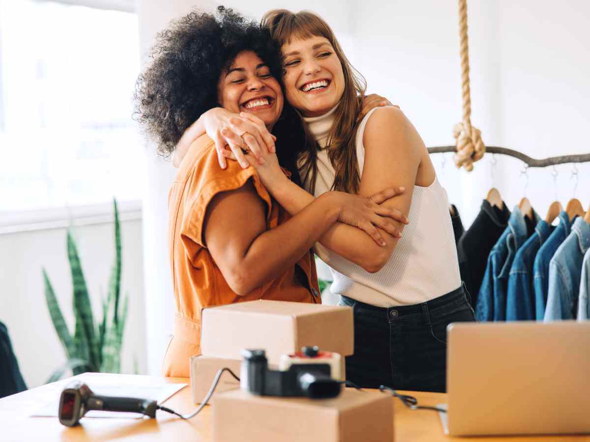 Succession Planning for Business Partners | Two female business partners embracing and smiling at the opening of their store.