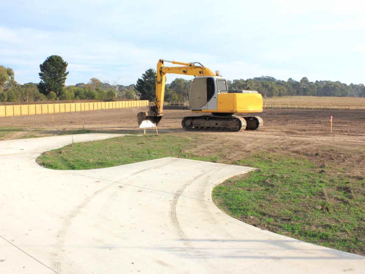 Yellow heavy duty earth moving machine on site in a new real estate subdivision in Australia.