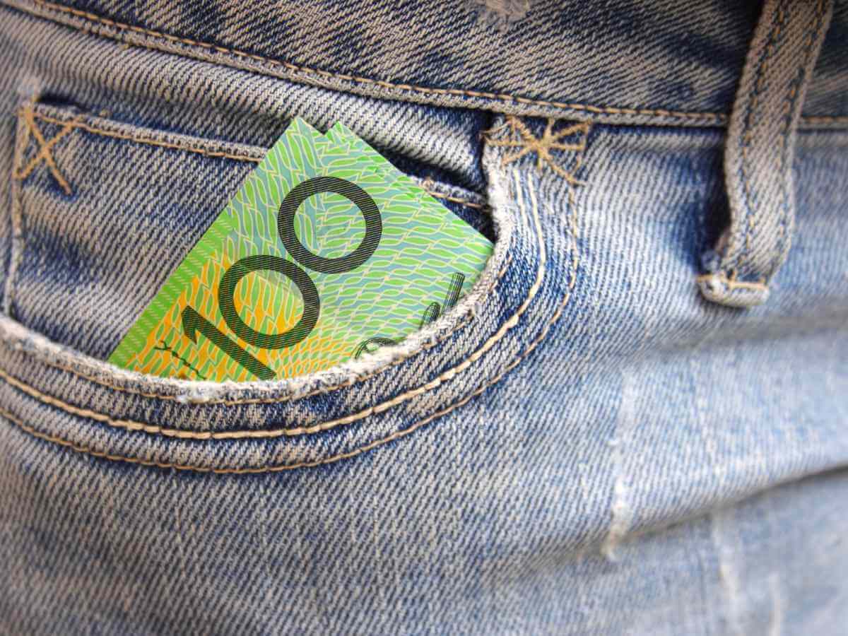 Image of an Australian one hundred dollar note sticking out of the pocket of faded blue denim jeans