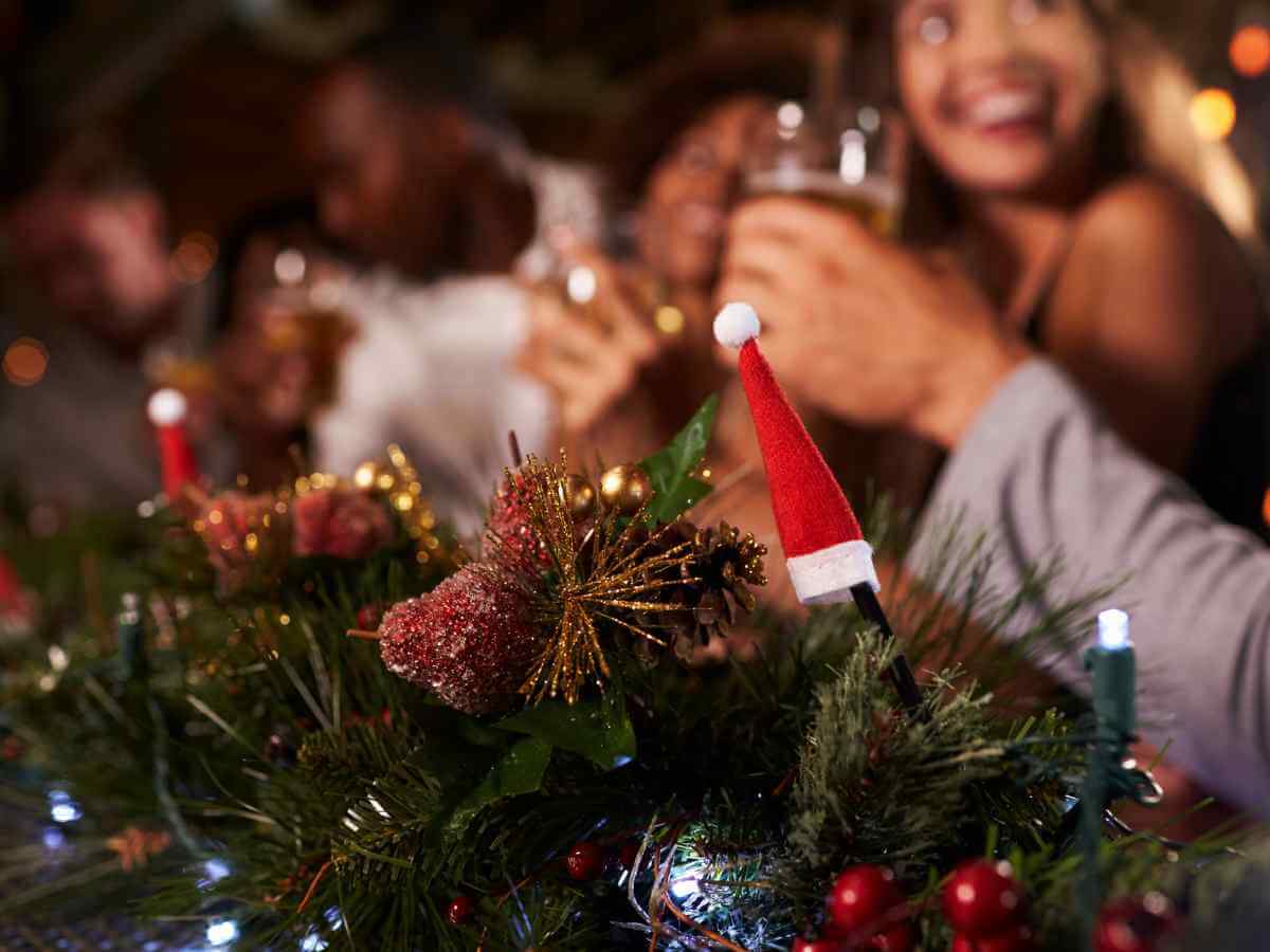 Image of festive people at an office Christmas party drinking champagne at a table covered in Christmas decorations