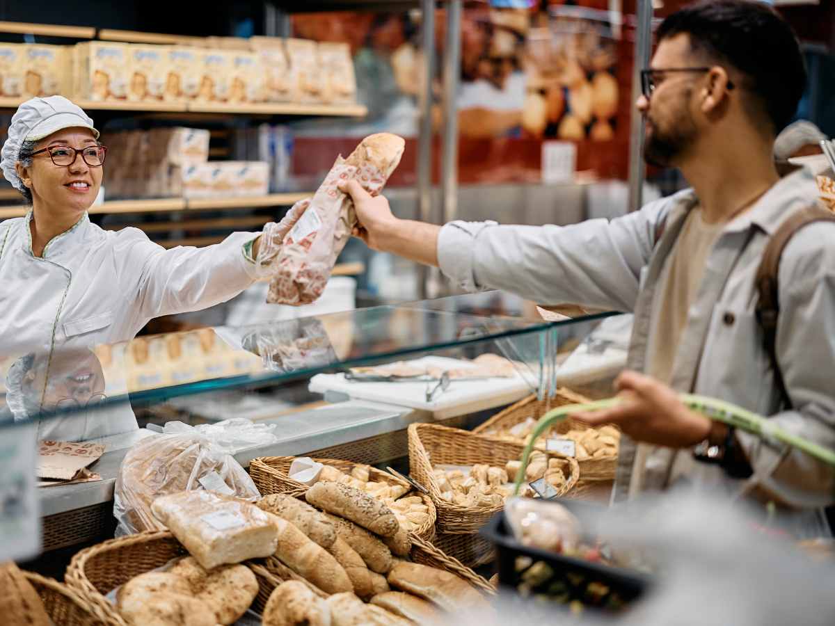 Debit and credit card surcharges banned | image of a man buying a loaf of bread at a bakery