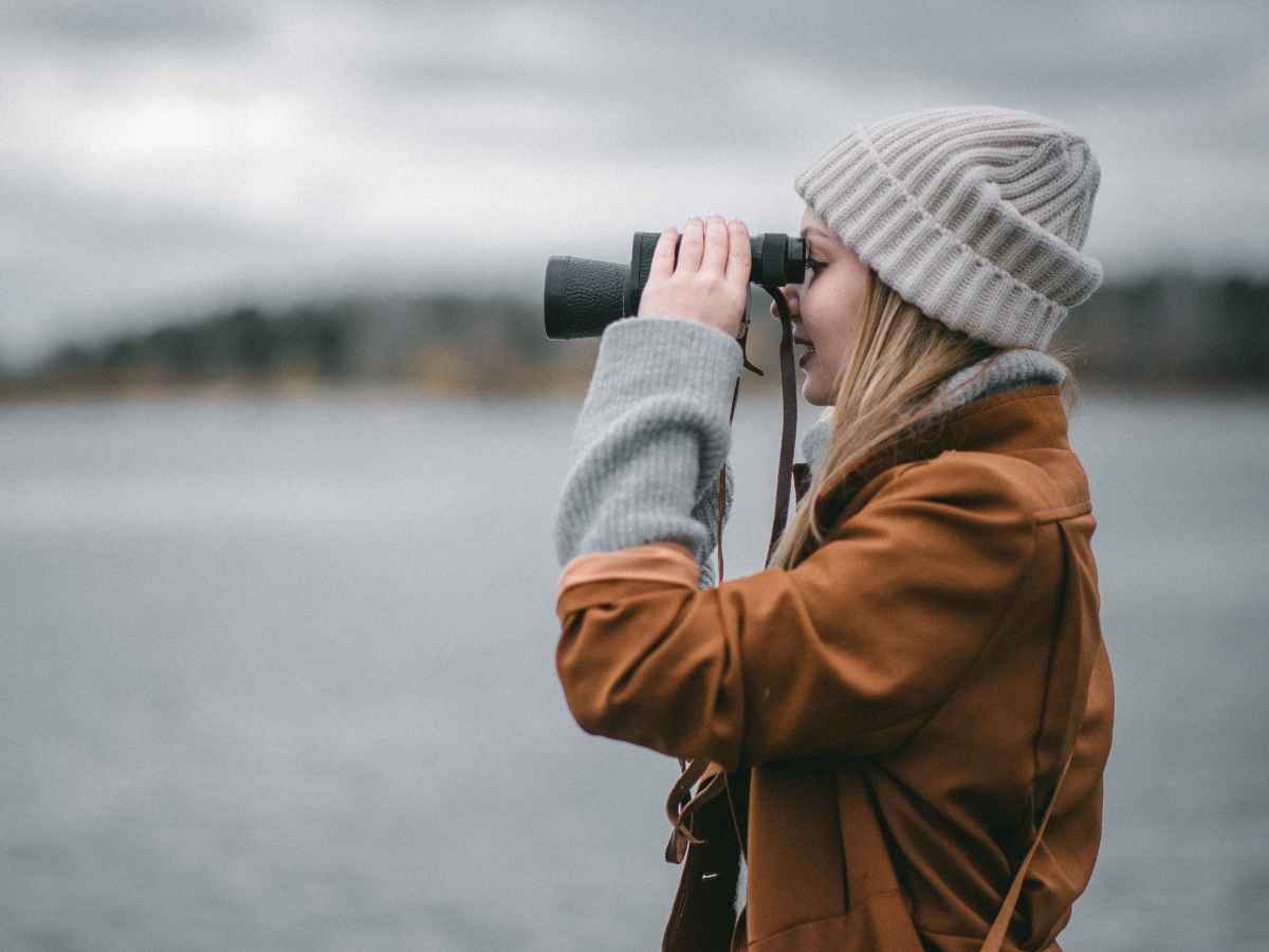 Lost super | image of a young female traveller on a remote shore using binoculars